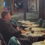 Muškarac i žena uživali u piću i cigareti dok Pariz gori u pozadini